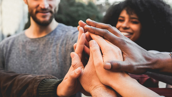 Menschen stehen im Kreis zusammen und geben High-Fives