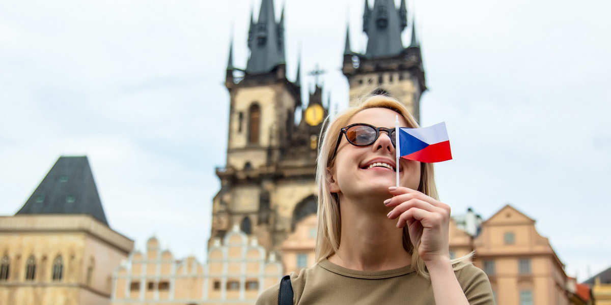 Eine Frau mit kleiner tschechischer Flagge in der Hand steht vor der Teynkirche in Prag