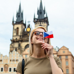 Eine Frau mit kleiner tschechischer Flagge in der Hand steht vor der Teynkirche in Prag