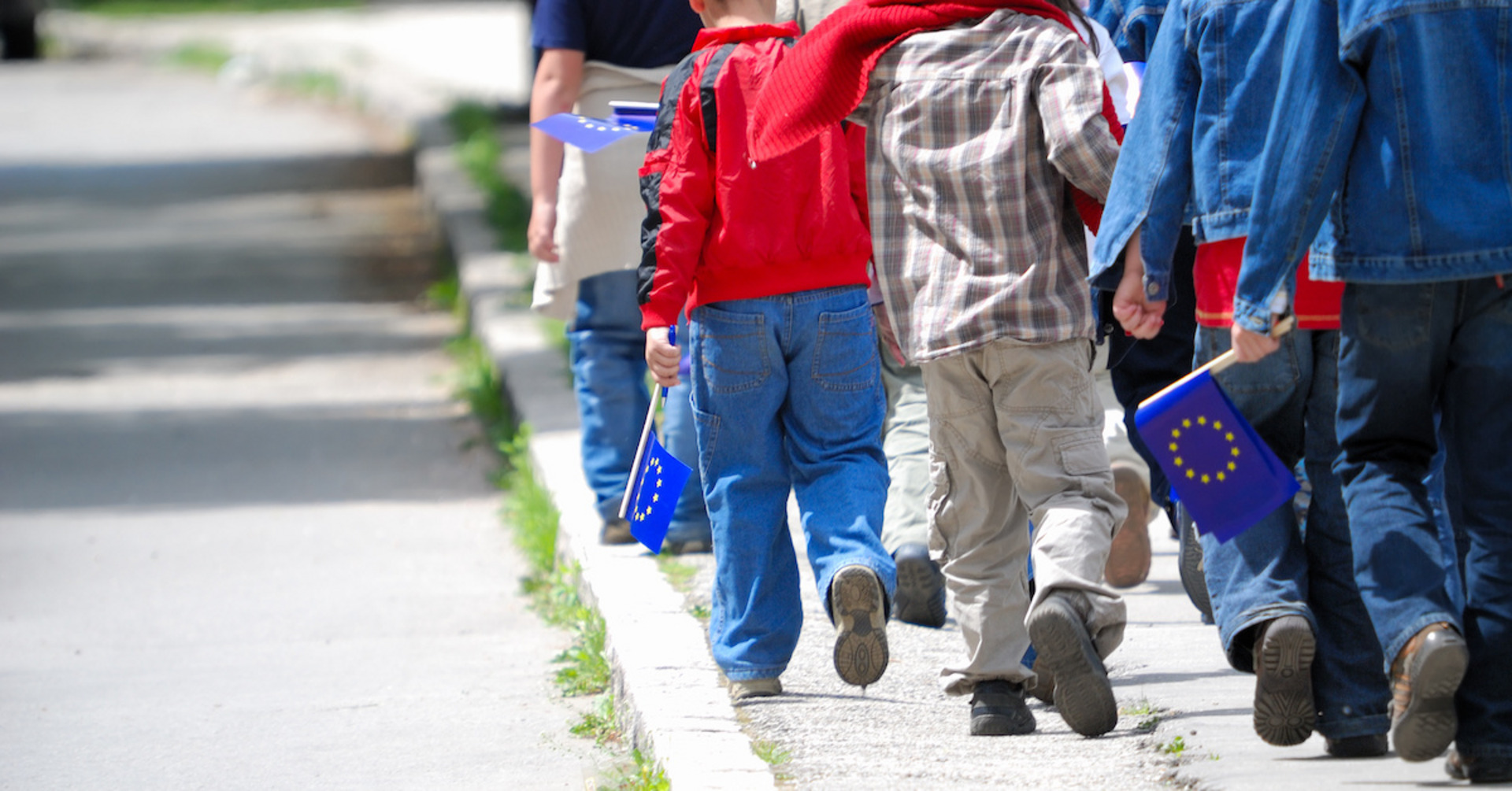 Kinder mit EU-Flaggen gehen auf dem Bürgersteig