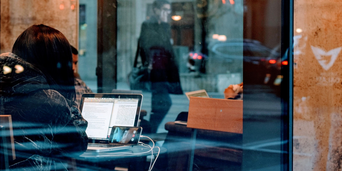 Eine Person sitzt in einem Café vor dem Laptop