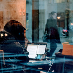 Eine Person sitzt in einem Café vor dem Laptop