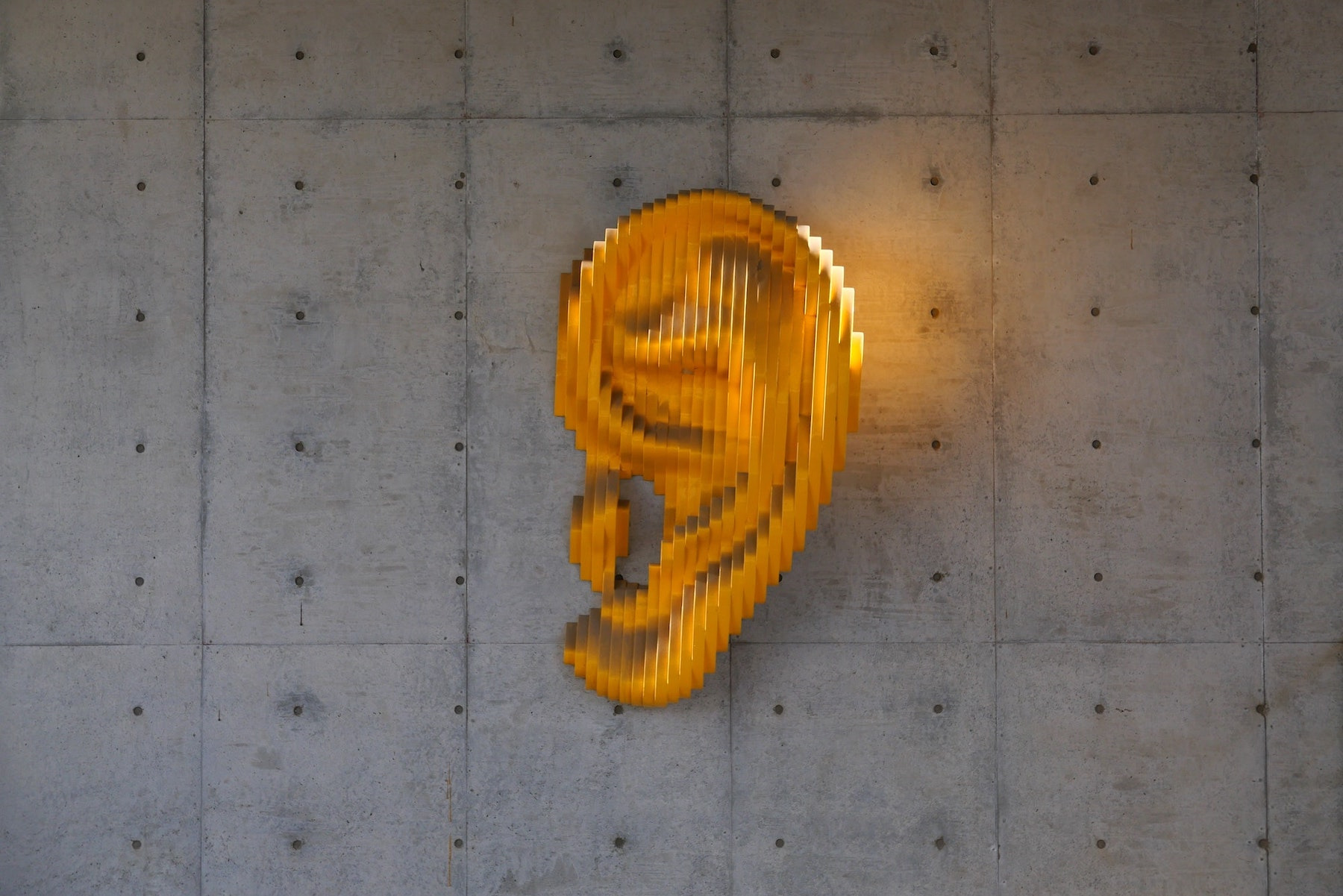 Ein Ohr aus Gold hängt als Kunstobjekt an einer Wand