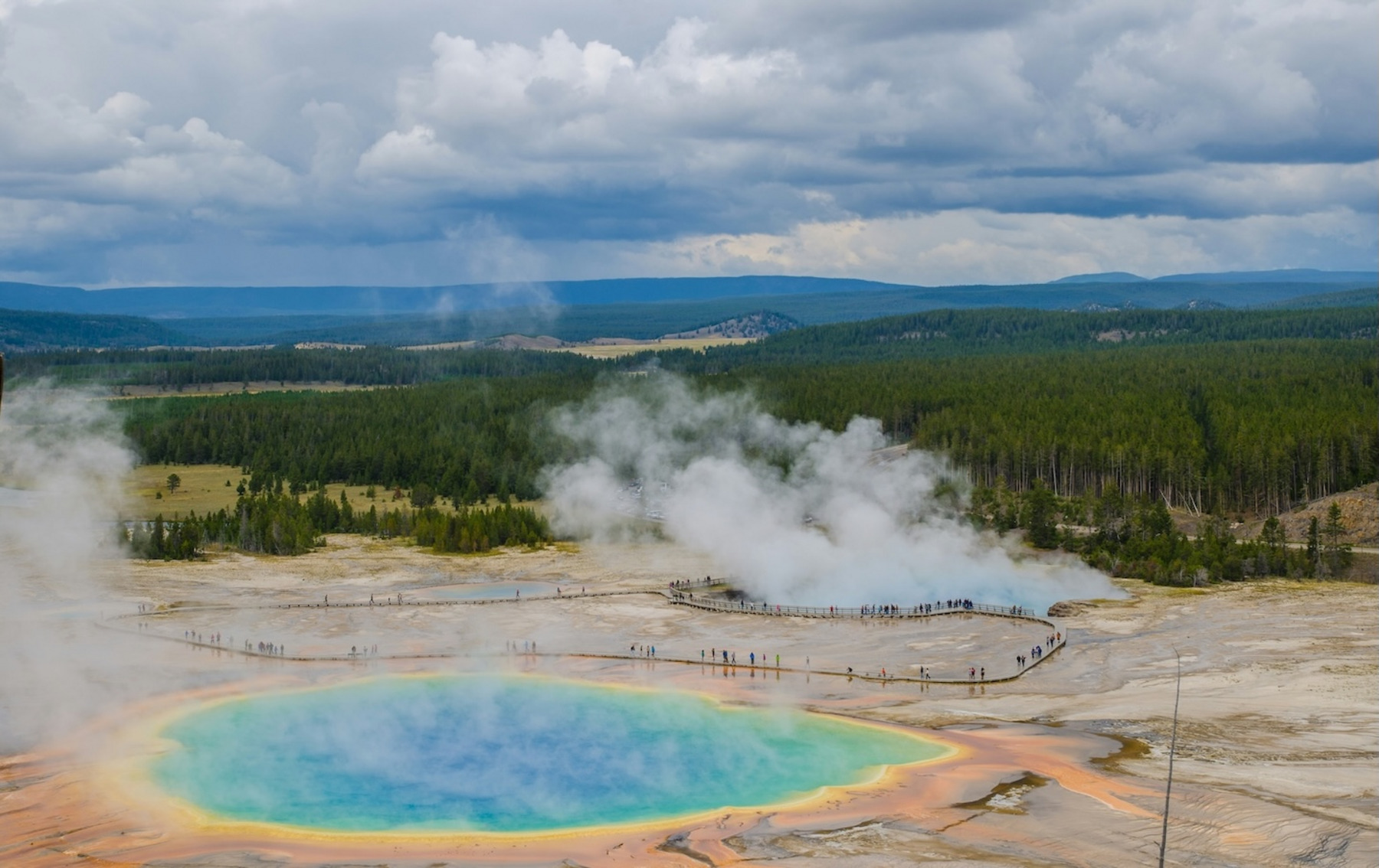 Die Grand Prismatic Spring, eine Thermalquelle, deren farbiges Wasser von Blau über Grün bishin zu gelb-orange reicht.