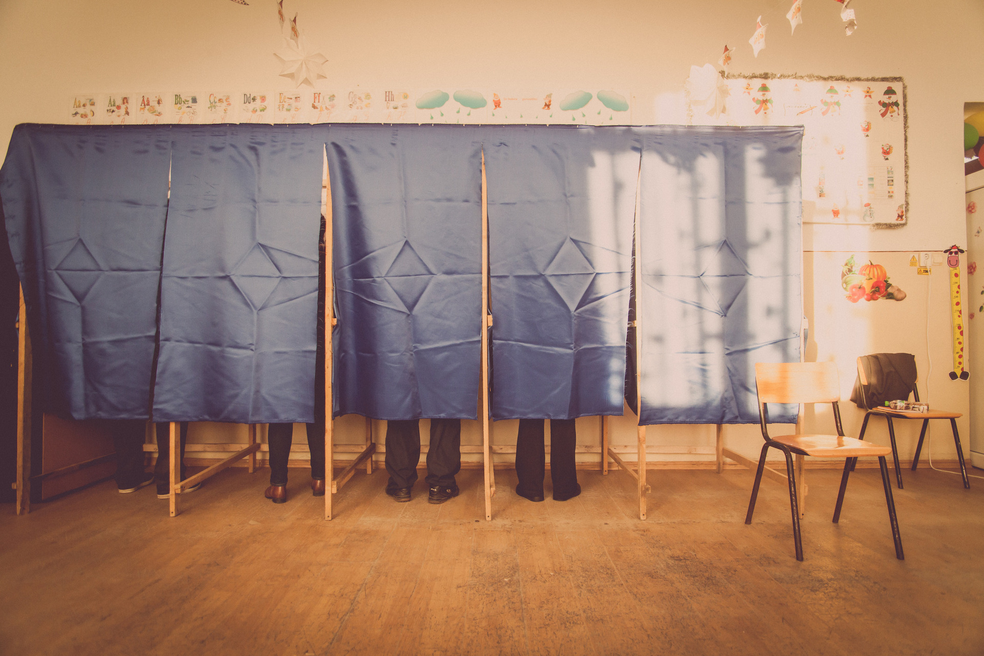Menschen stehen hinter Vorhängen in Wahlkabinen