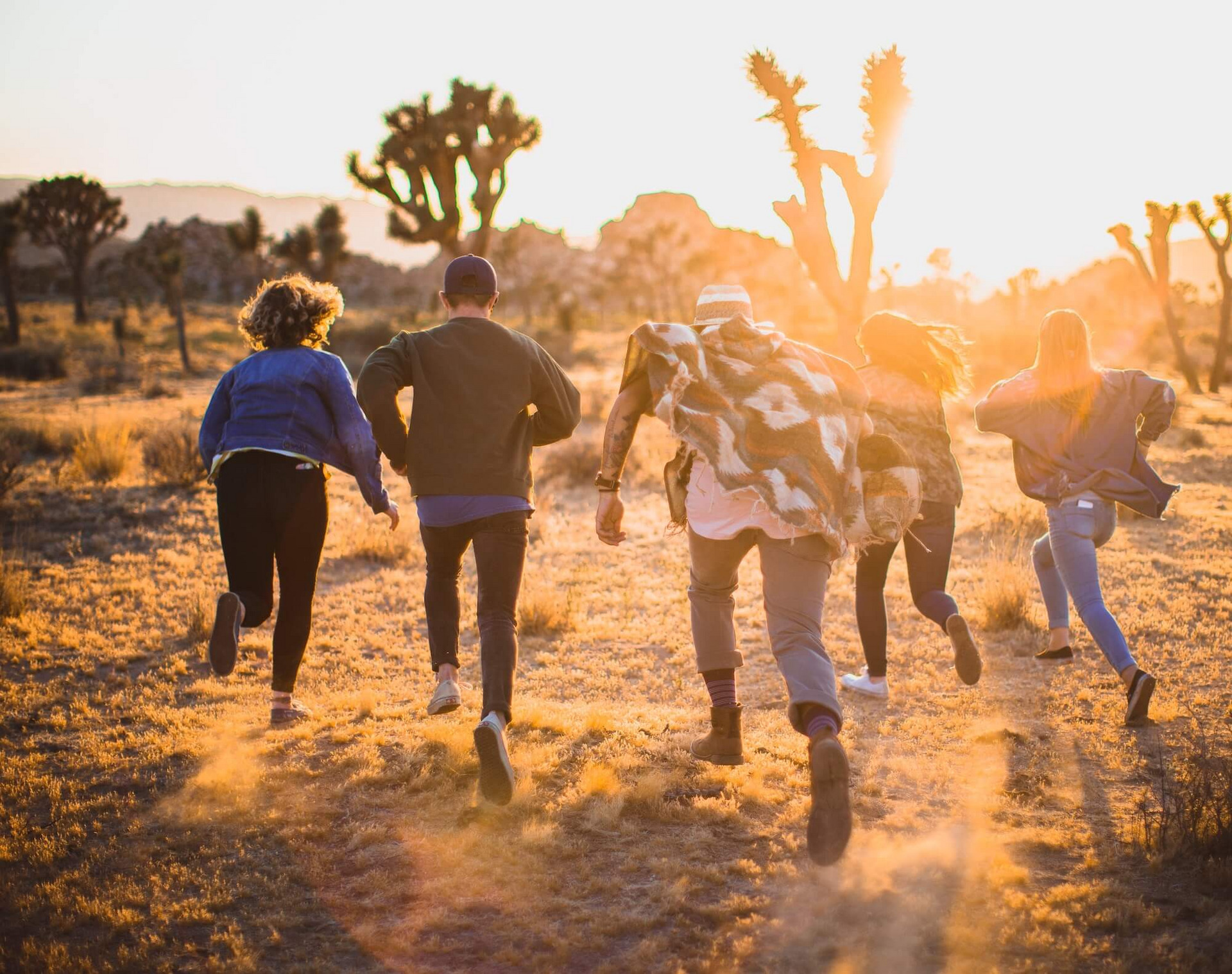 Eine Gruppe junger Menschen rennt durch di Wüste