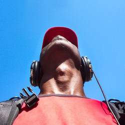 Eine Person mit Kopfhörern und einem roten T-Shirt schaut in den blauen Himmel.