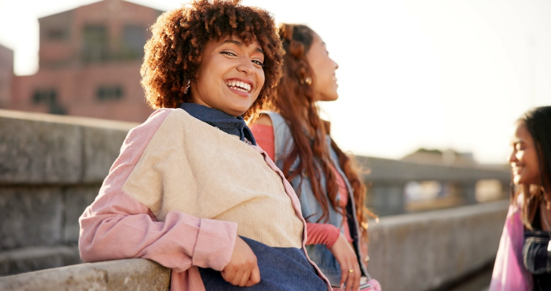 Drei junge Frauen lachen miteinander auf einer Dachterrasse