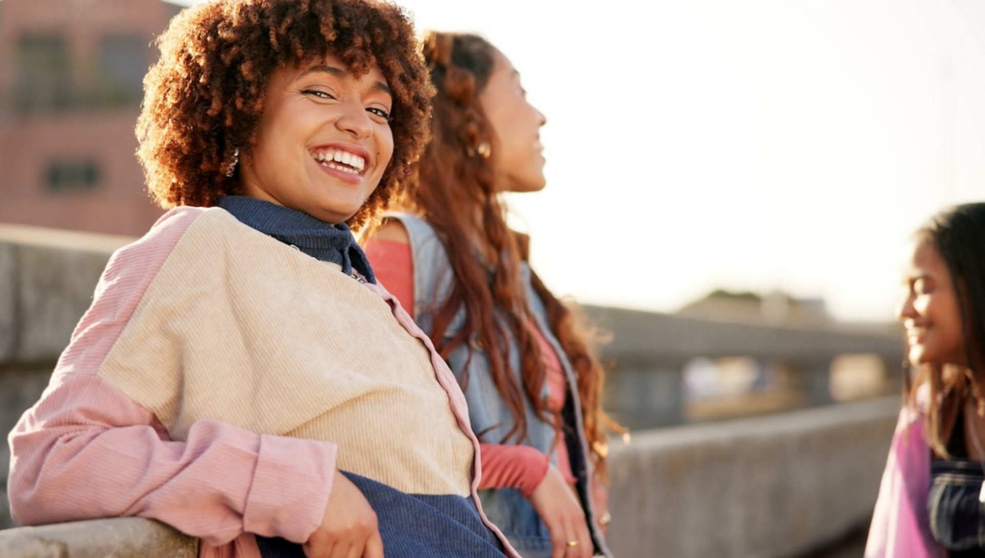 Drei junge Frauen lachen miteinander auf einer Dachterrasse