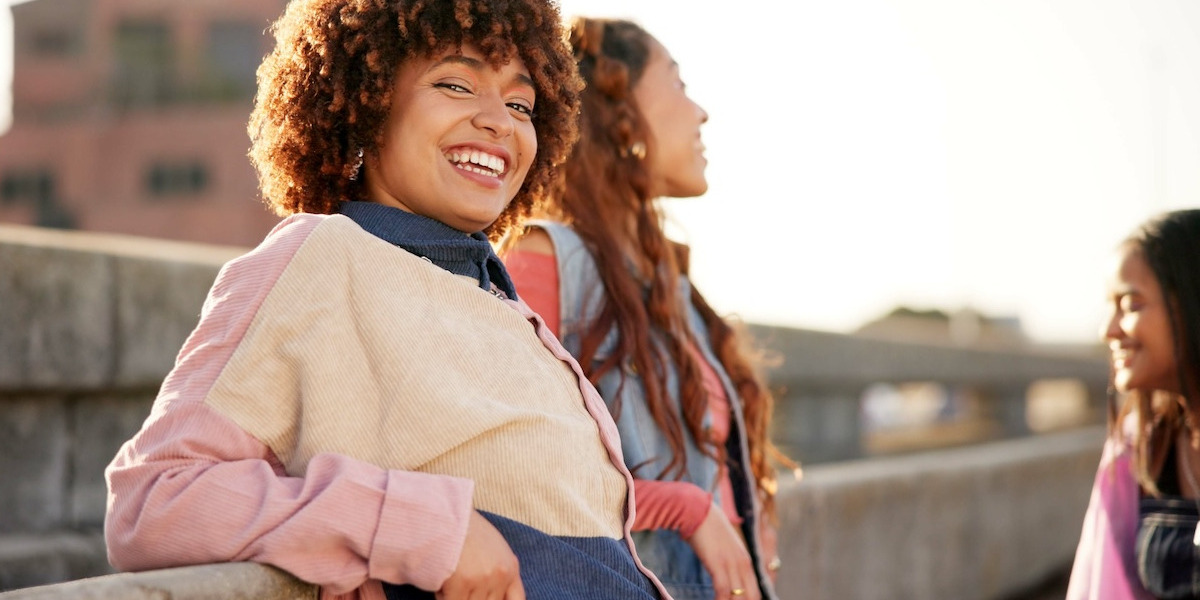 Drei junge Frauen lachen miteinander auf einer Dachterrasse