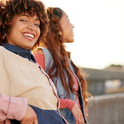 Drei junge Frauen lachen miteinander auf einer Dachterrasse