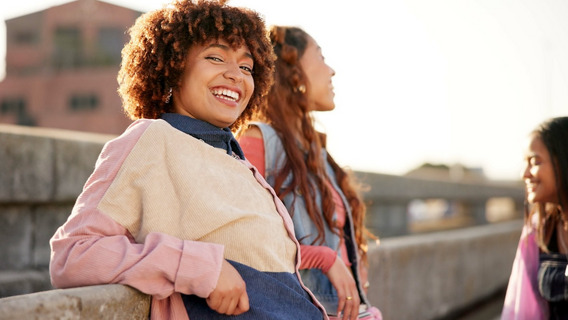 Drei junge Frauen lachen miteinander auf einer Dachterrasse