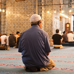 Personen beten auf den Knien in einer Moschee