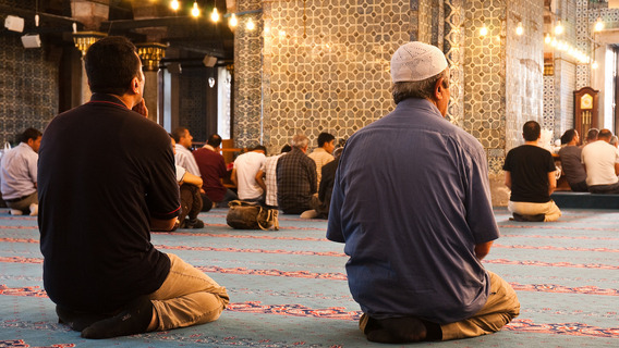Personen beten auf den Knien in einer Moschee