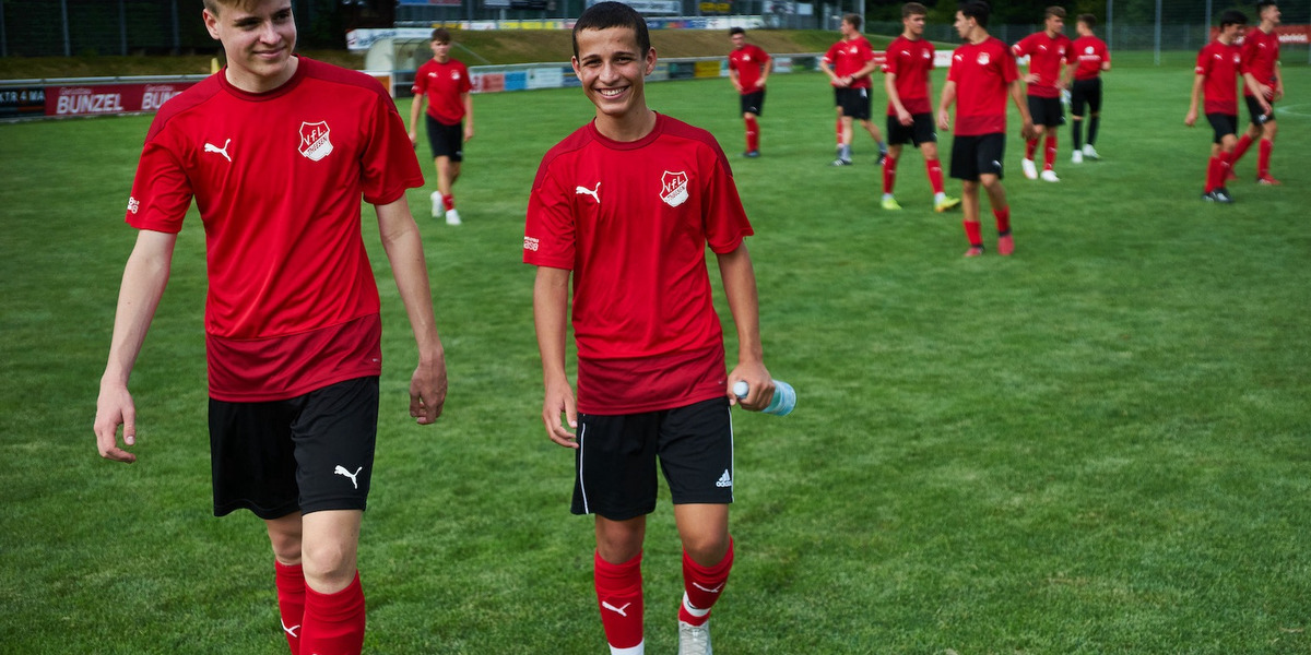 Fußballmannschaft auf dem Spielfeld in roten Trikots