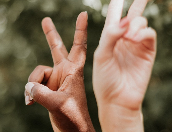 Zwei junge Menschen recken die Hände mit gespreizten Fingern zum Peace-Zeichen empor.