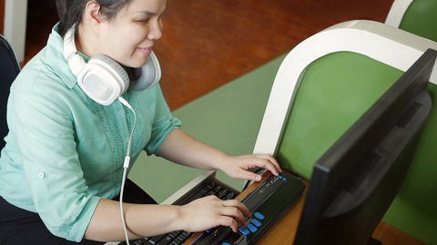 Eine blinde Frau bedient einen Computer mithilfe eines Screenreaders.