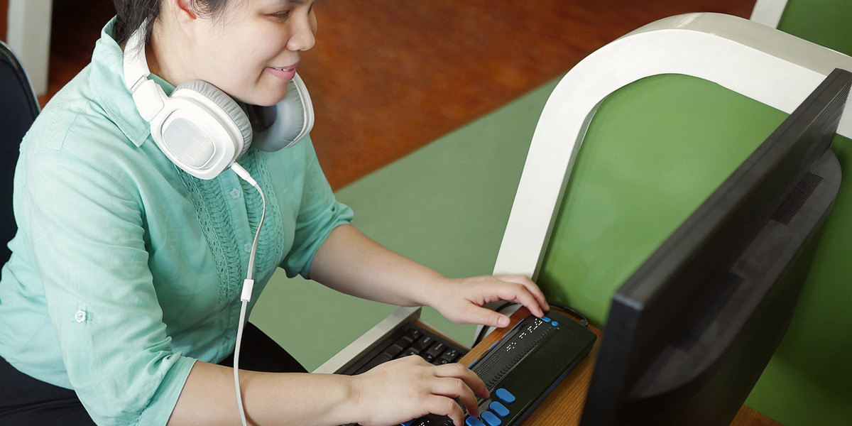 Eine blinde Frau bedient einen Computer mithilfe eines Screenreaders.