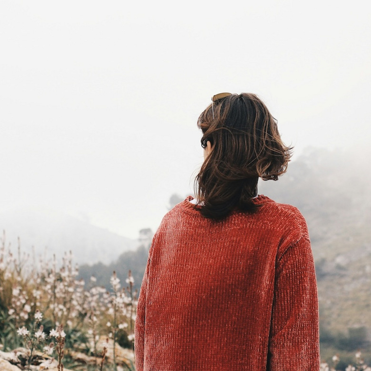Eine Frau blickt auf eine karge Berglandschaft im Nebel