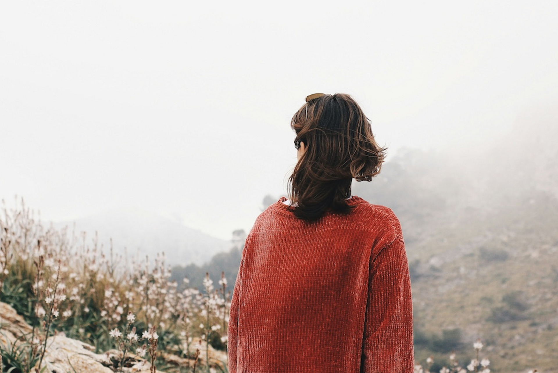 Eine Frau blickt auf eine karge Berglandschaft im Nebel