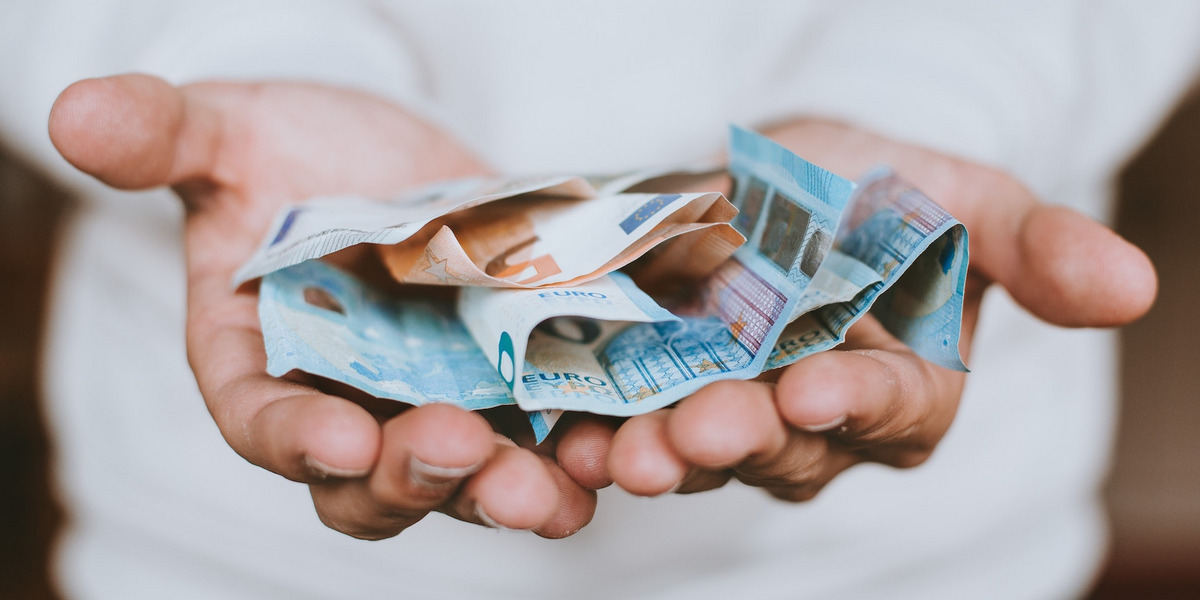 Eine Person hält die Hände auf, in denen sich Geldscheine befinden