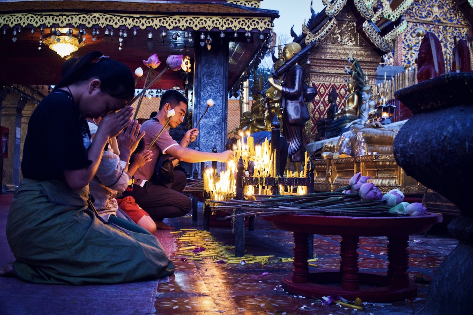 Menschen beten und zünden Kerzen an in einem Tempel.