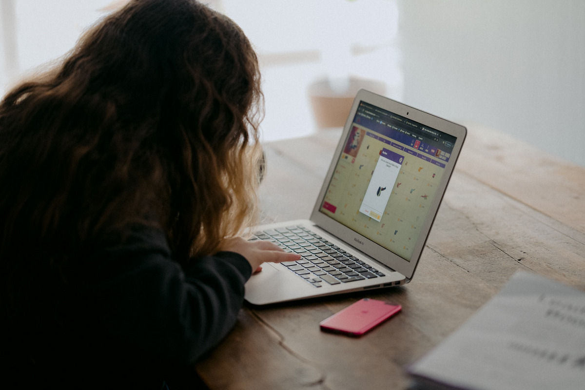 Eine junge Frau schaut auf ihren Laptop, in dessen Browserfenster eine Online-Lernanwendungen geöffnet ist