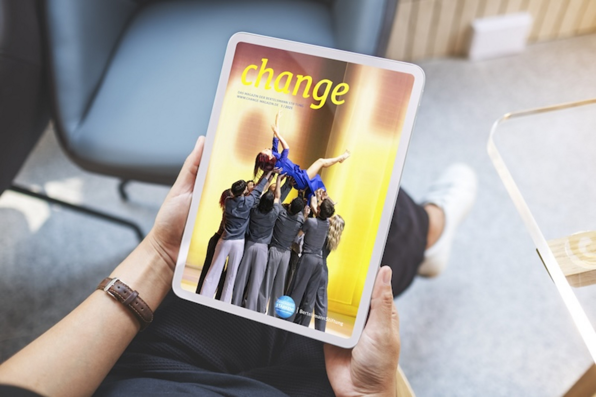 Zu sehen sind Hände, die ein iPad halten, auf dem die Titelseite des PDF-Magazins von change zu sehen ist
