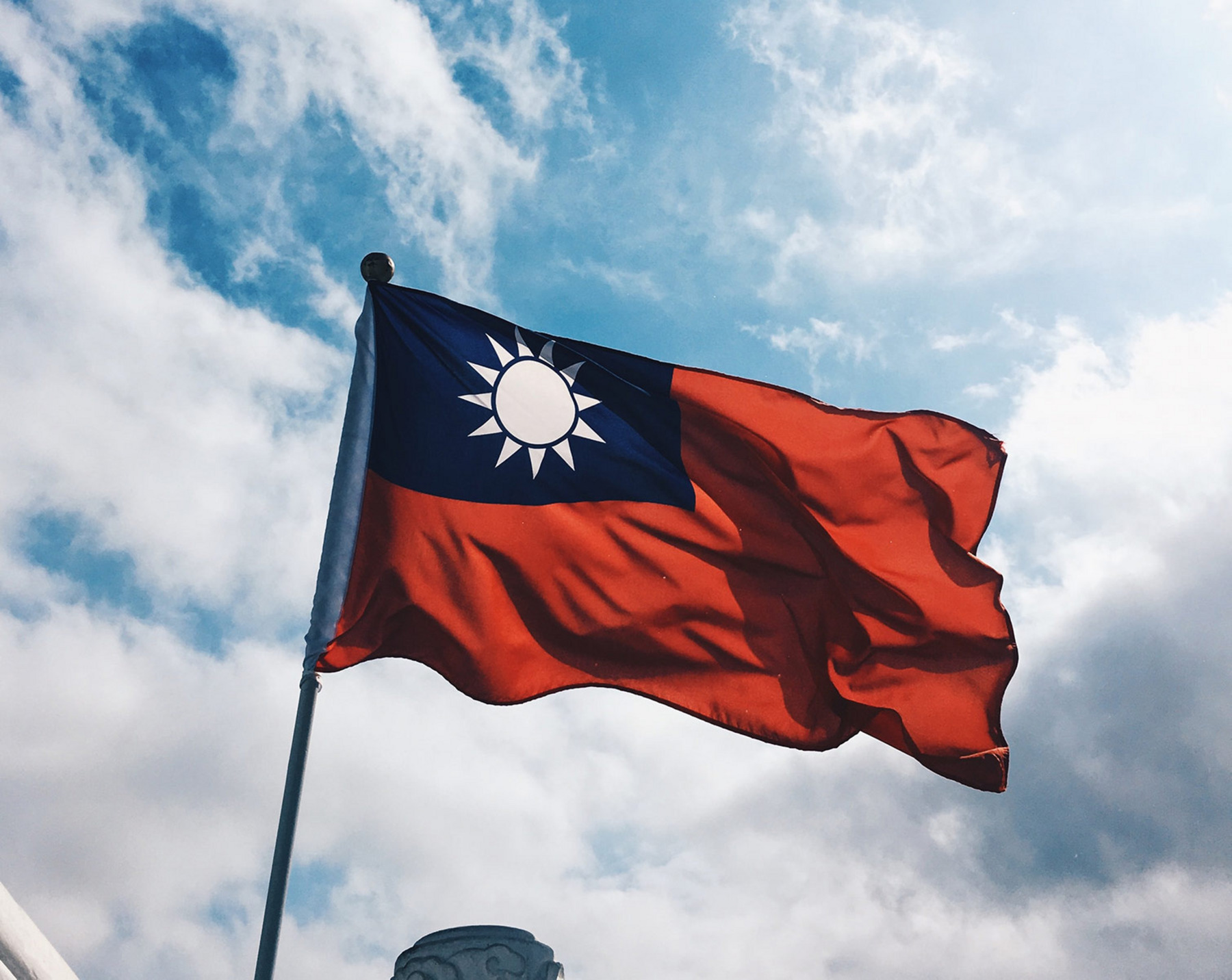 Die Flagge der Republik China weht im Wind vor einem strahlend blauen Himmel. Die Flagge ist rot mit einer weißen Sonne auf blauem Grund im oberen linken Viertel