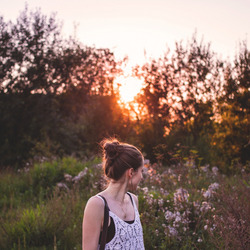 Eine junge Frau steht in der Abendsonne in der Natur