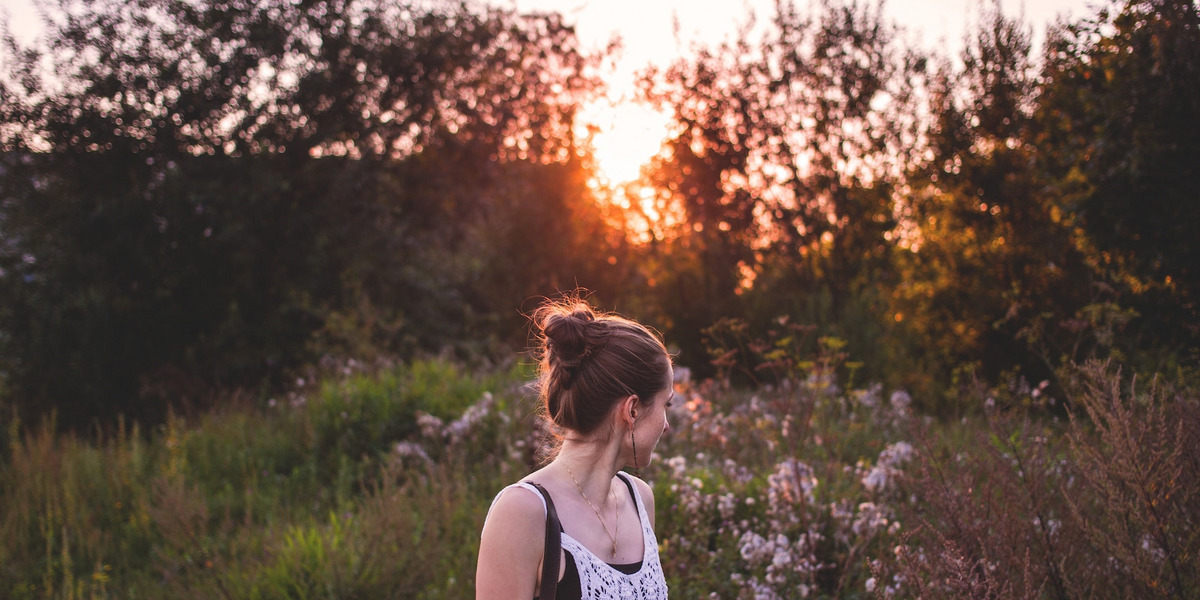 Eine junge Frau steht in der Abendsonne in der Natur
