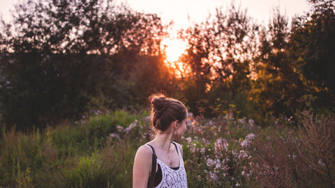 Eine junge Frau steht in der Abendsonne in der Natur
