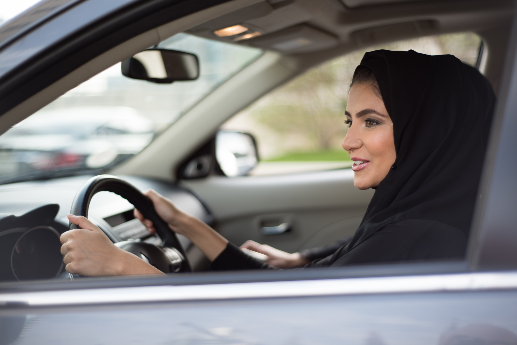 Eine Niqab tragende Frau sitzt auf dem Fahrersitz eines Auto.