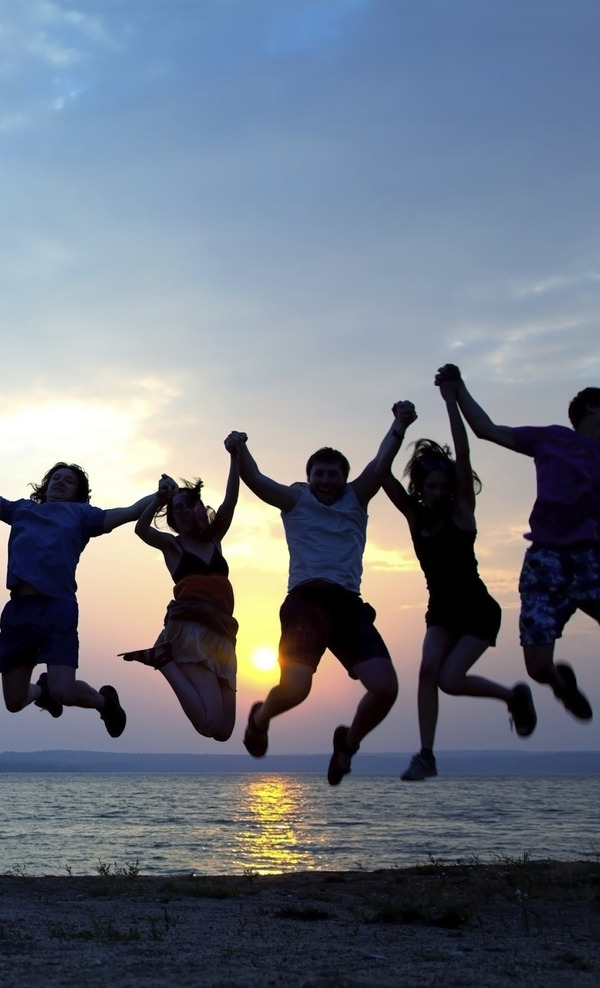 Eine Gruppe von Jugendlichen springen beim Sonnenuntergang hoch.