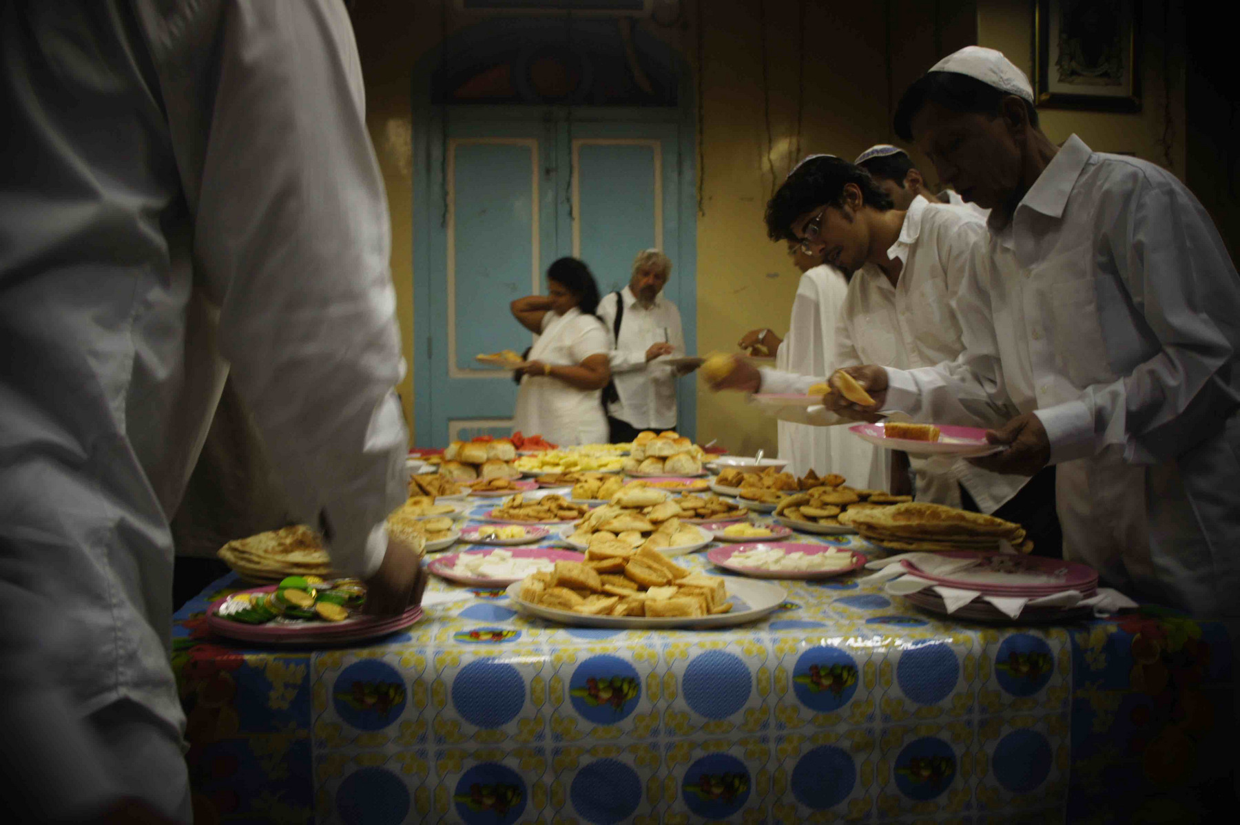 Viele Menschen stehen um einen Tisch mit Essen und brechen das Fasten nach Jom Kippur