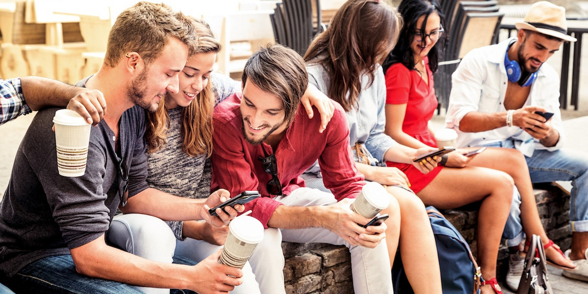 Jugendliche sitzen zusammen und schauen auf ihre Smartphones