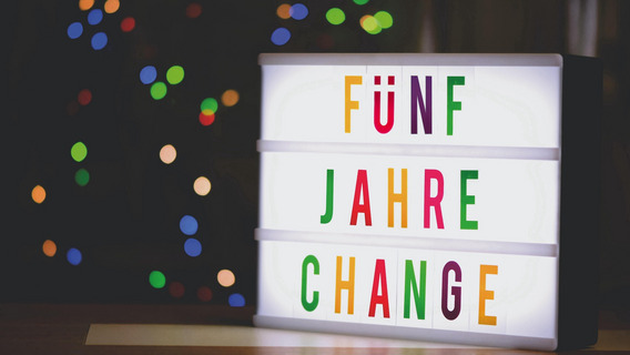 Ein Foto eines Leuchtkastens, in dem mit bunten Buchstaben steht "FÜNF JAHRE CHANGE".