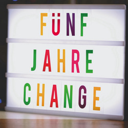 Ein Foto eines Leuchtkastens, in dem mit bunten Buchstaben steht "FÜNF JAHRE CHANGE".