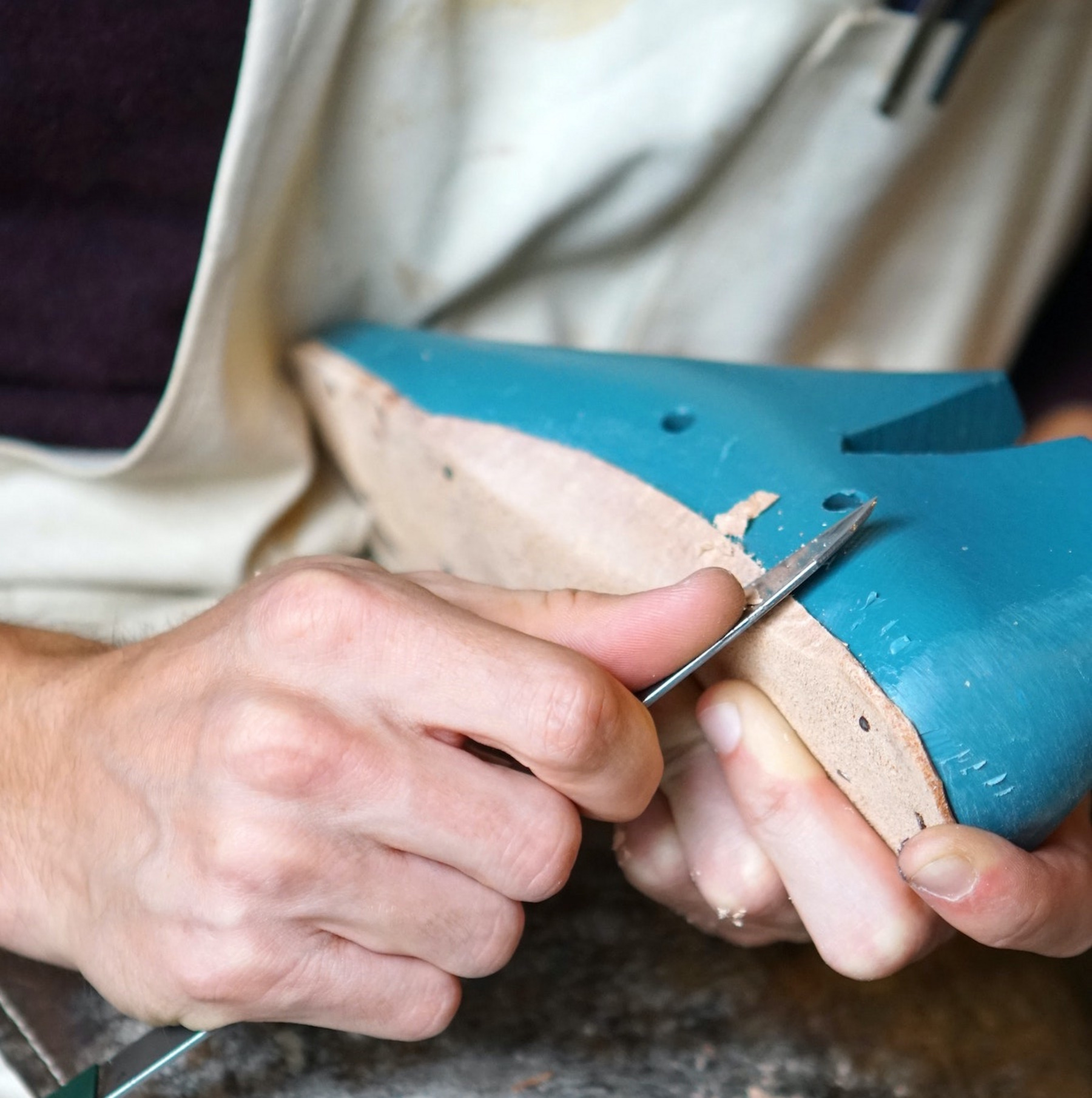 Ein:e Schuster:in arbeitet an einem Schuh