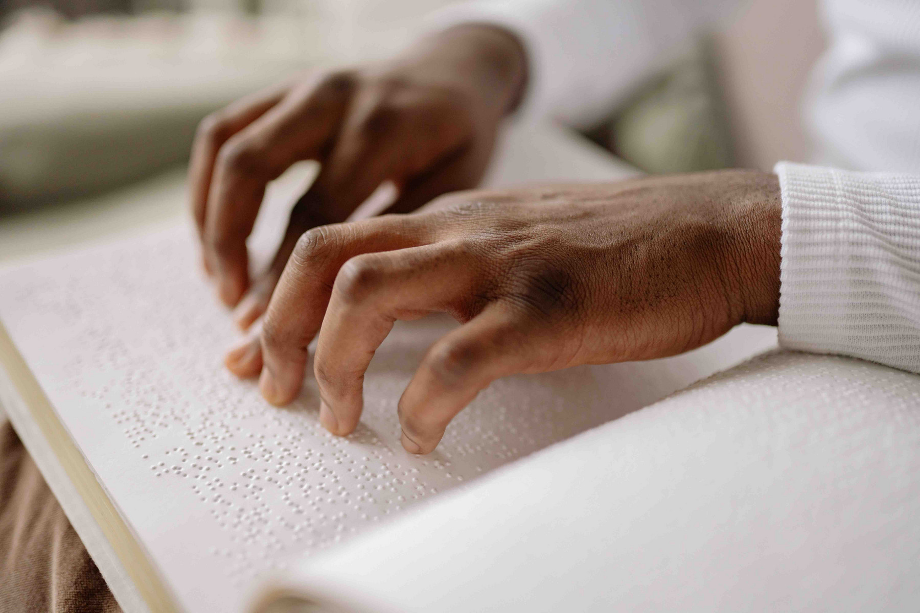 Die von Louis Braille erfundene Blindenschrift: Finger fahren über ein Buch.