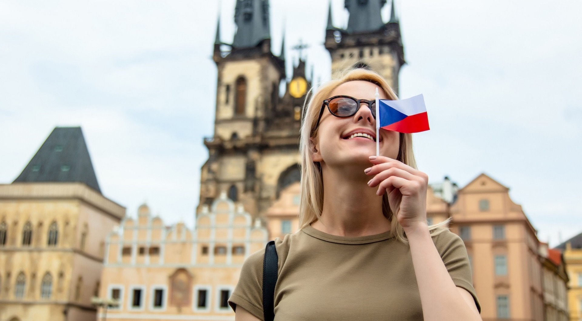Eine Frau mit kleiner tschechischer Flagge in der Hand steht vor der Teynkirche in Prag