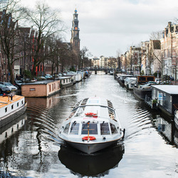Ein Ausflugsboot fährt durch eine Gracht in Amsterdam