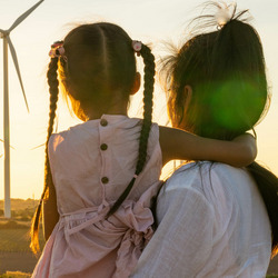 Im Vordergrund eine Frau mit einem kleinen Mädchen auf dem Arm, im Hintergrund ein Feld mit Windmühlen.