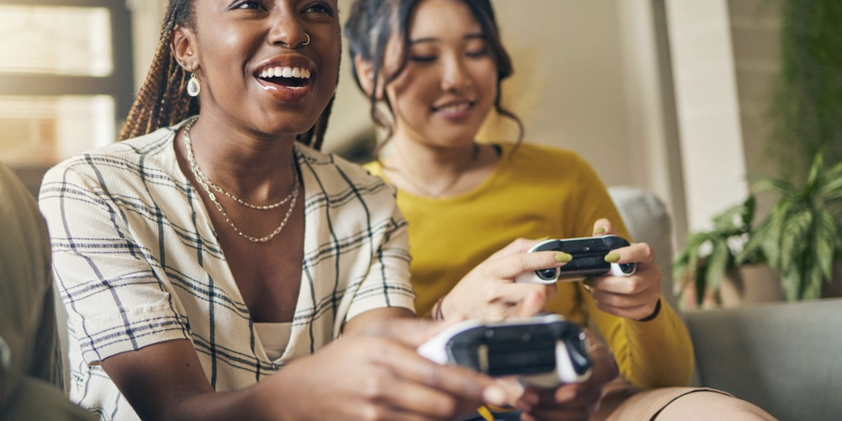 Zwei junge Frauen sitzen mit Spielekonsole auf dem Sofa
