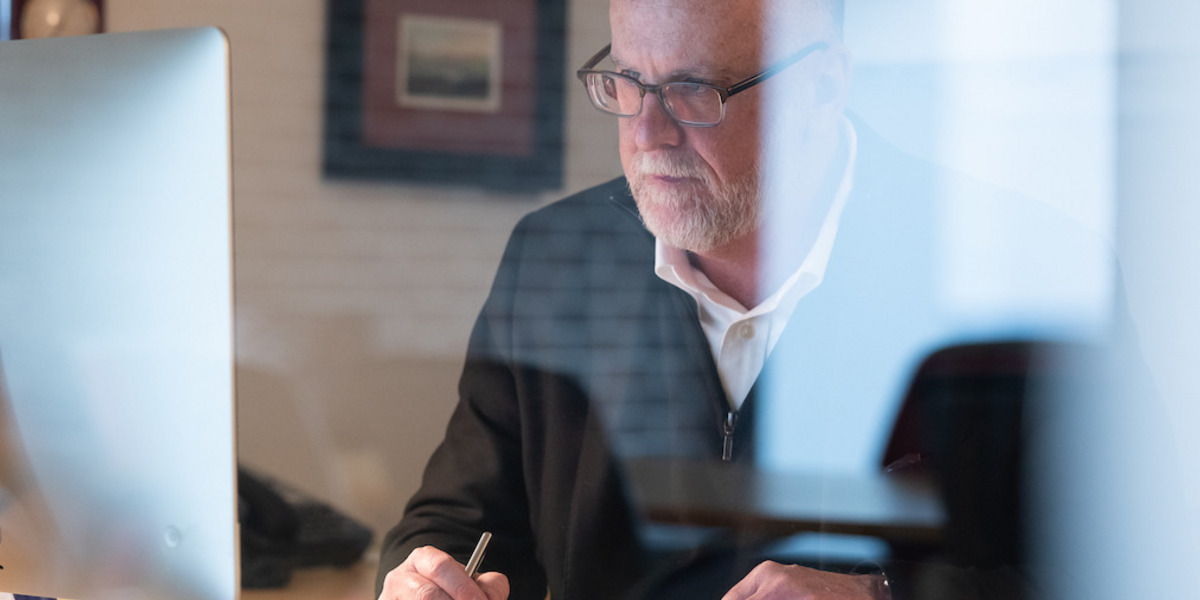 Ein Mann mit Brille sitzt vor seinem Computer mit einem Stift in der Hand.