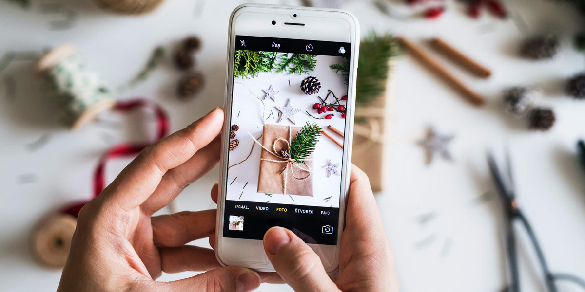 Jemand fotografiert Weihnachtsgeschenke mit dem Handy