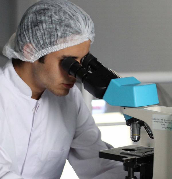 Ein Mann im Laborkittel schaut in ein Mikroskop.