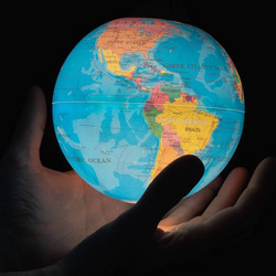 Eine Person hält einen beleuchteten Globus in den Händen