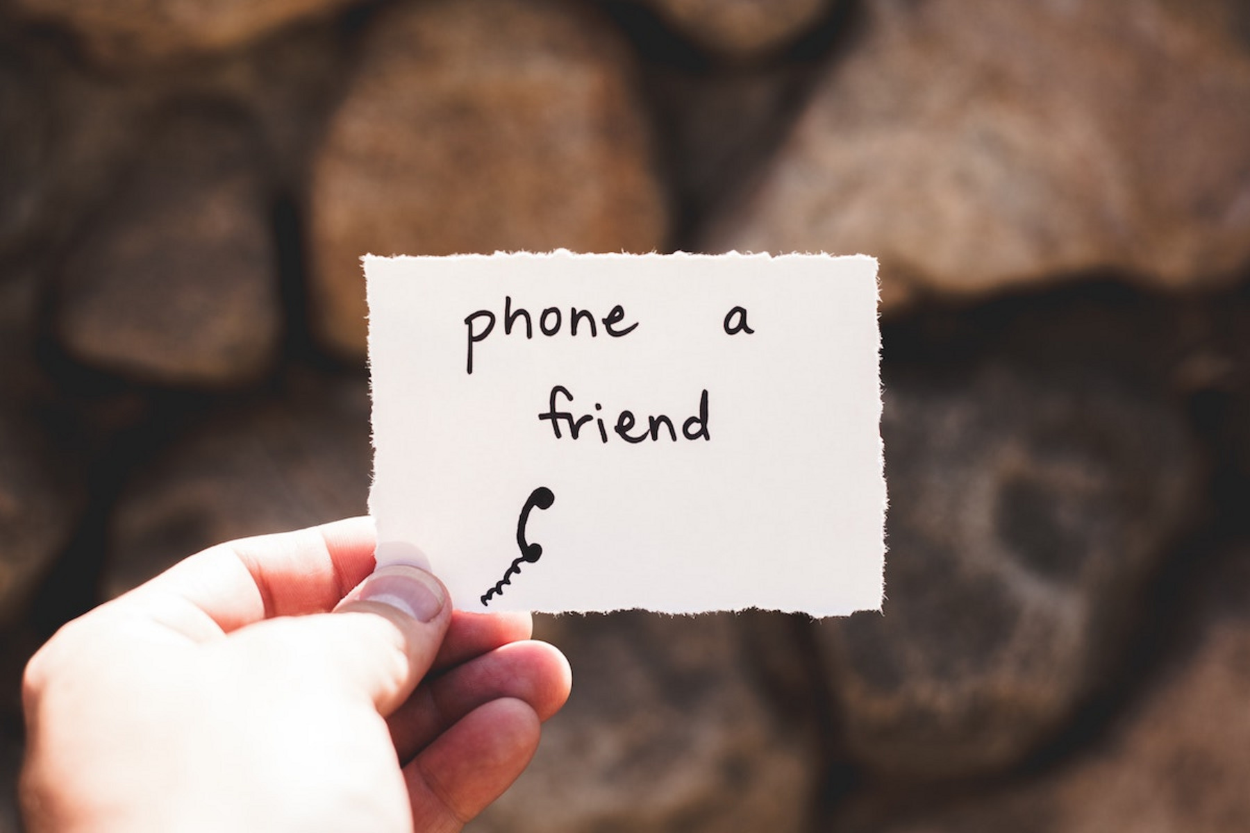Eine Person hält einen Zettel mit dem Text "phone a friend".