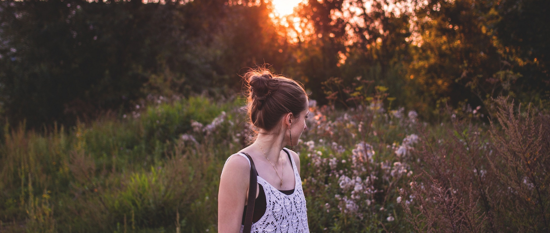 Eine Junge Frau steht in der Abendsonne in der Natur